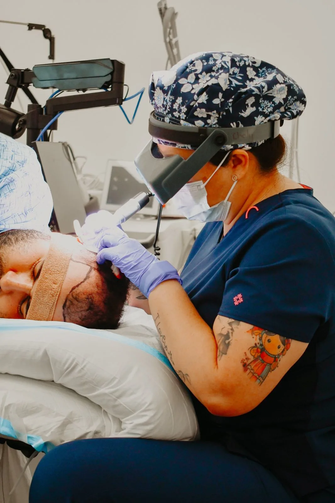 Dermatologist wearing a headlamp and protective gear examines a patient's face during a skin treatment procedure